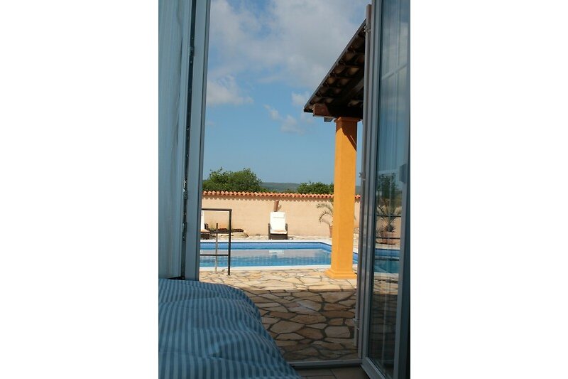Blick vom blauen Schlafzimmer auf Terrasse und Pool
