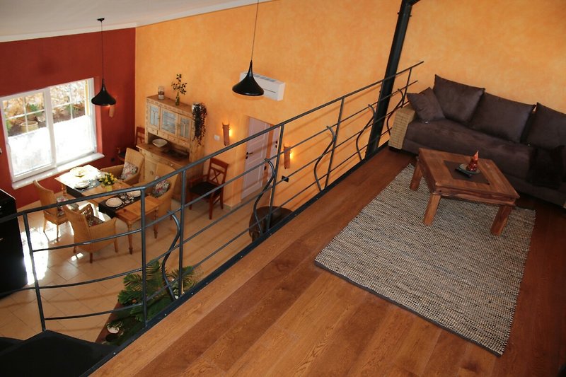 Wendeltreppe zur Galerie mit Sitzgruppe und TV - Die Couch ist ausziehbar als Schlafplatz für 2 Personen