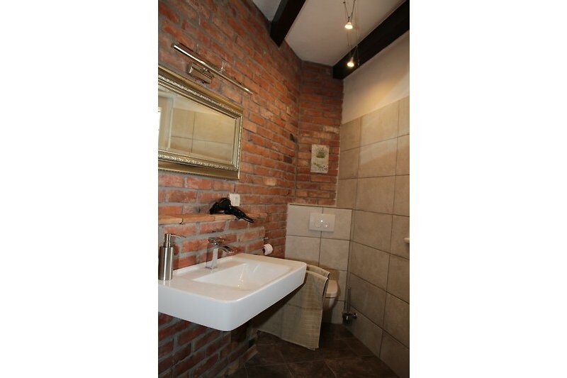 Ein stilvolles Badezimmer mit Holzboden, Keramikwaschbecken und Spiegel.