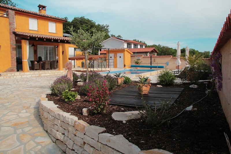 Ein charmantes Haus mit einer gepflasterten Einfahrt und einem grünen Garten - perfekt zum Entspannen im Urlaub.