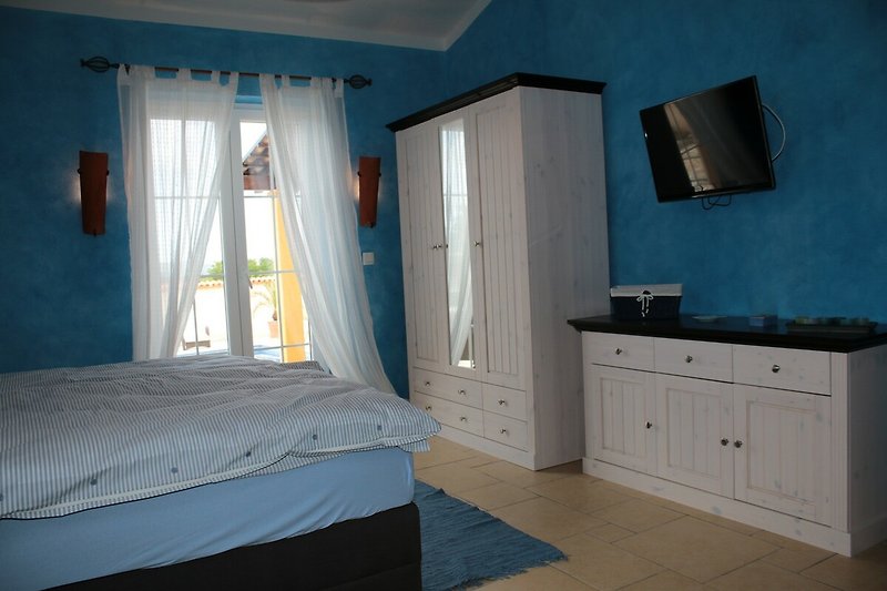 Ein gemütliches Schlafzimmer mit Holzmöbeln und blauen Vorhängen.