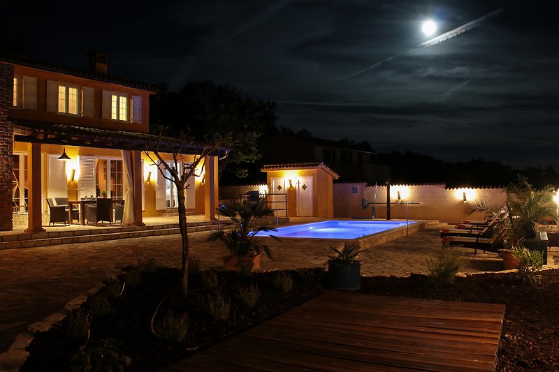 Ein Abend mit beleuchtetem Haus und Pool - perfekt für Ihren Urlaub.