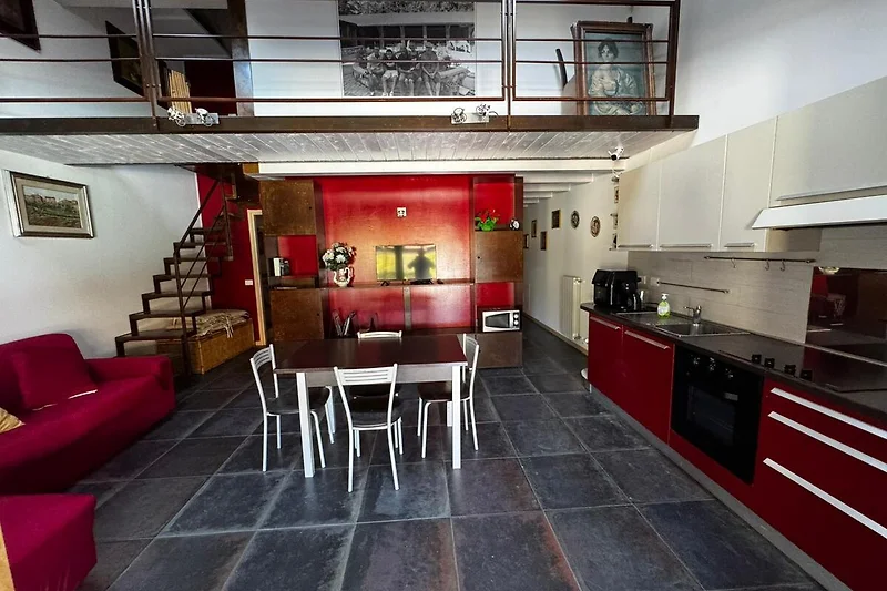 Offener Wohnbereich mit Sofa, Sessel, Esstisch und Küchenzeile.