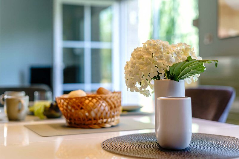 Einladender Tisch mit stilvollem Geschirr und blühender Pflanze.