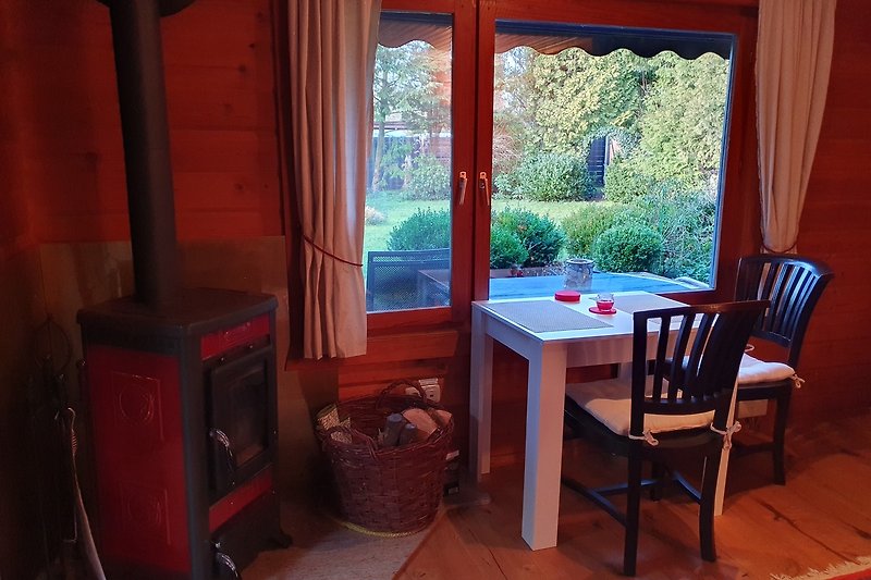 Heideblockhaus Erika - Gemütliches Wohnzimmer mit Kaminofen und Blick in den Garten