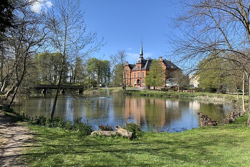 Das charmante Schloss von Schönhagen mit Blick auf einen See und eine malerische Landschaft.