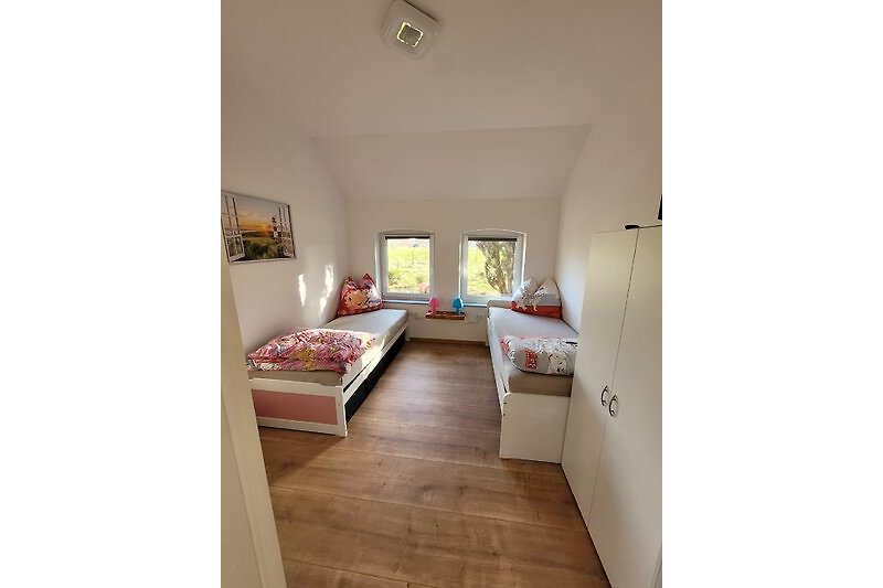 Gemütliches Kinder Schlafzimmer mit Holzboden und stilvollem Fenster.