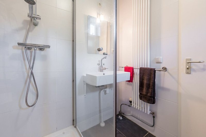 A modern bathroom with sleek fixtures and a glass shower panel.