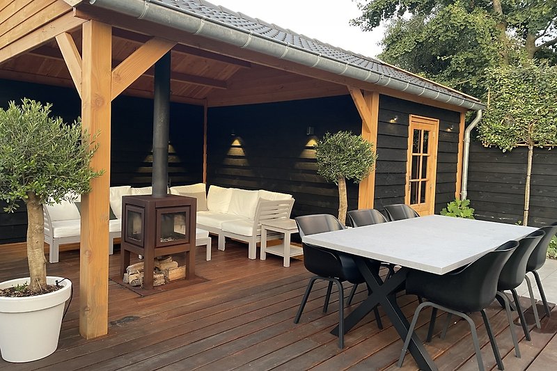 Houten overdekte veranda in de achtertuin met houtkachel om te genieten van de zomeravonden
