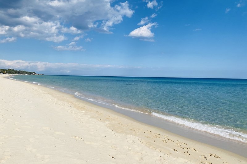 Ein ruhiger Strand mit azurblauem Wasser, weißem Sand und mediterraner Brise.