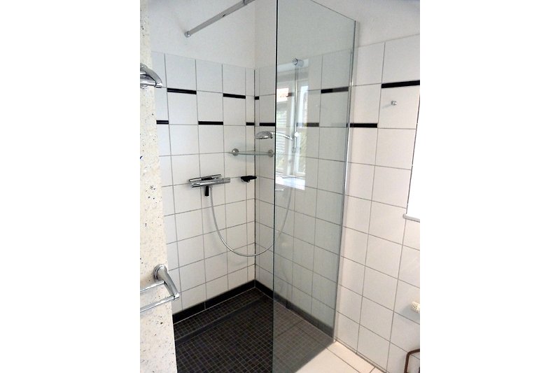 Modernes Badezimmer mit stilvollem Interieur und gläserner Duschtür.