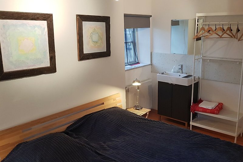 Schlafzimmer mit Waschbecken, Spiegel und Kunst.