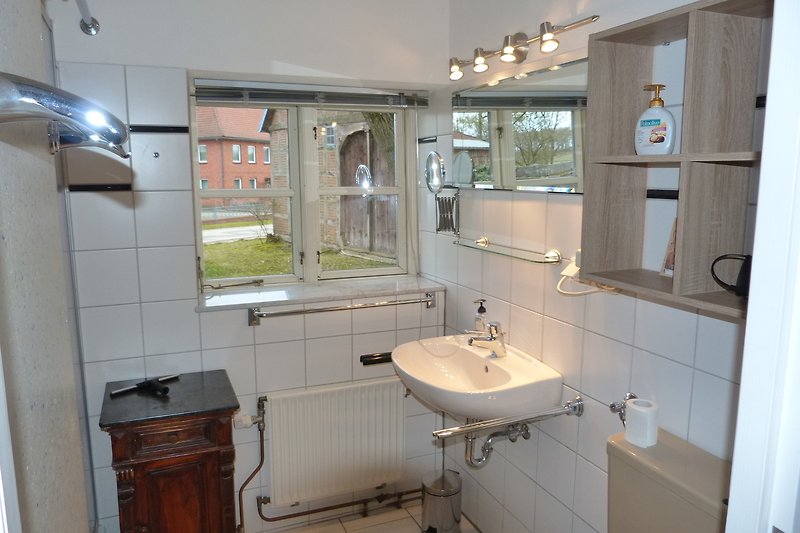 Badezimmer mit Spiegel, Waschbecken und Fenster.