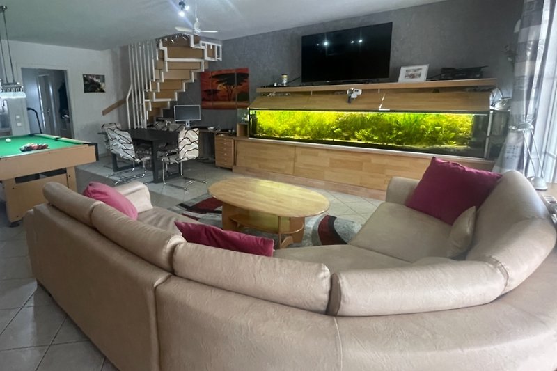 Gemütliches Wohnzimmer mit einem Aquarium und bequemer Couch.