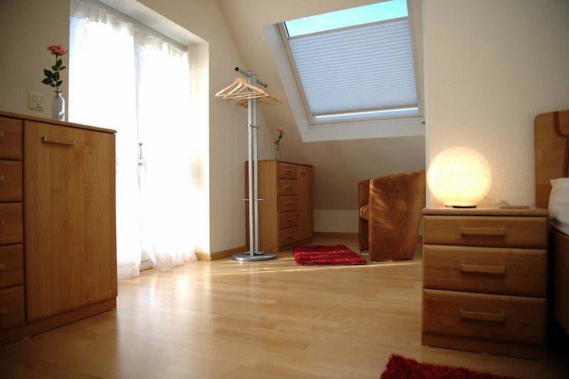 Gemütliches Schlafzimmer 2. OG mit stilvoller Beleuchtung, Holzmöbeln und gemütlicher Sitzgelegenheit.