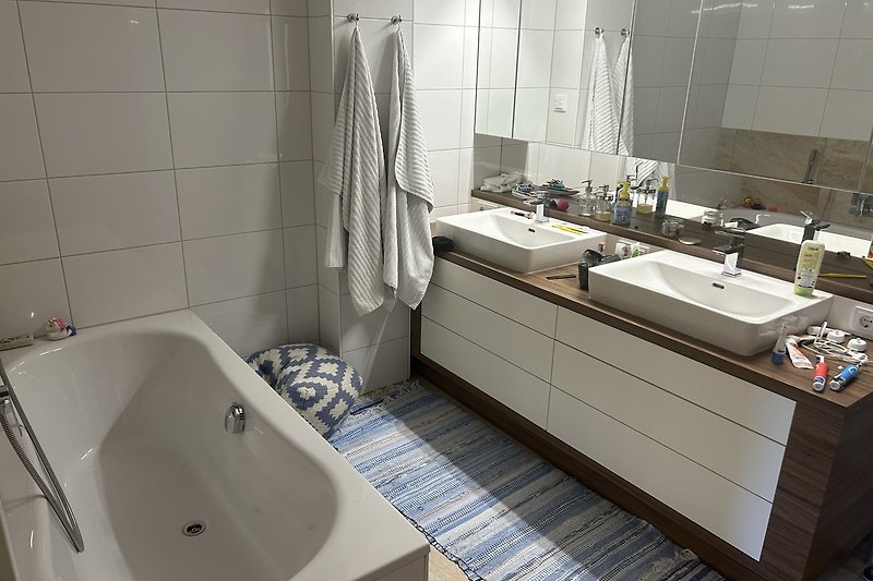 Moderne Badezimmer mit stilvoller Badewanne, Waschbecken und Spiegel.