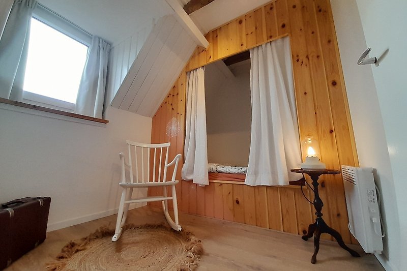 Holzinterieur mit Bett, Vorhängen und natürlichem Licht.