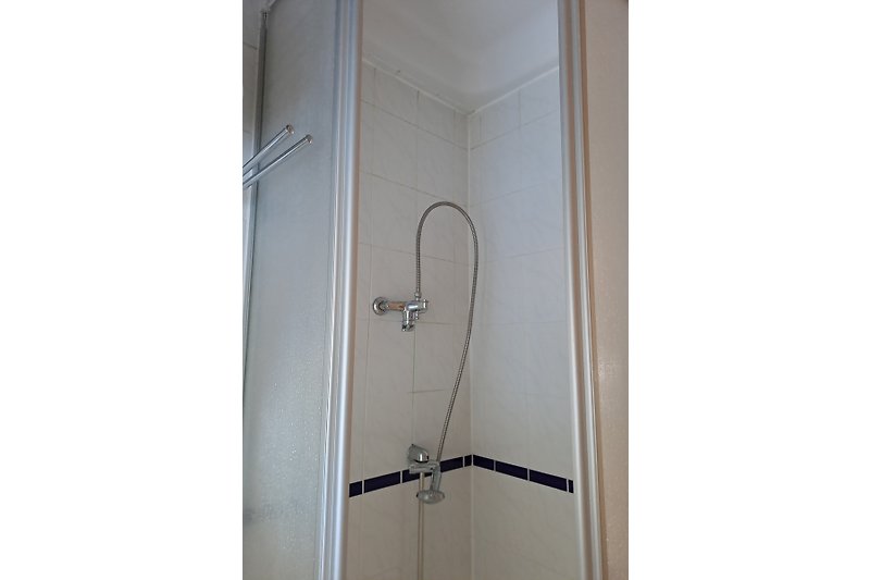 Gemütliches Badezimmer mit Glasdusche und Metallarmaturen.