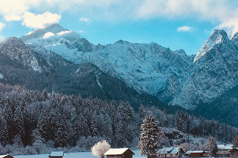 Beeindruckende Berglandschaft mit schneebedeckten Gipfeln und malerischem Haus.