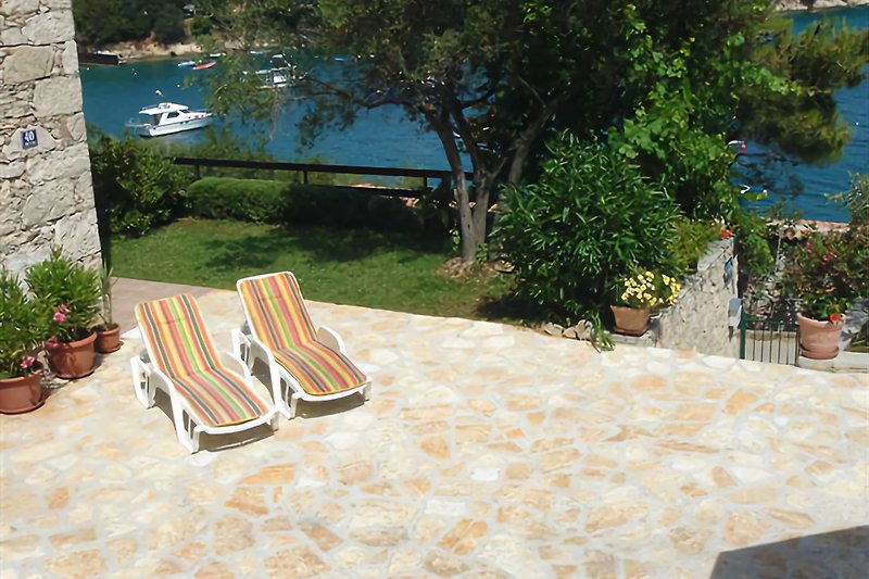 Predivan mediteranski vrt s udobnim lezaljkama za suncanje.
