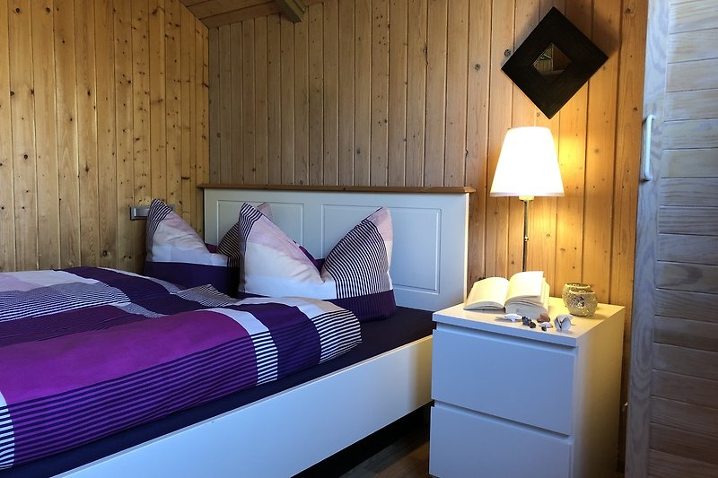Ein weiteres Schlafzimmer mit gemütlichem Holzbett und stilvoller Beleuchtung.