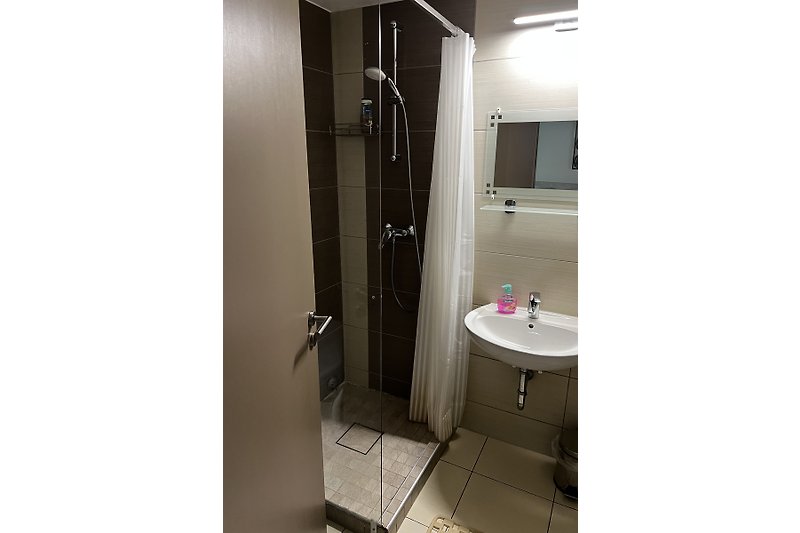 Gemütliches Badezimmer mit Waschbecken und rechteckigem Spiegel.