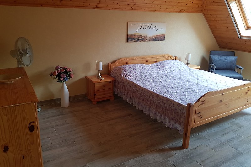 Gemütliches Schlafzimmer mit Holzbett und stilvoller Bettwäsche.