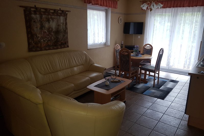 Gemütliches Wohnzimmer mit brauner Couch, Tisch und Fenster.