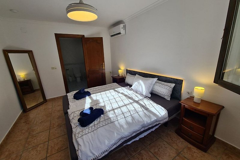 Dormitorio con iluminación bonita con ventilador de techo y aire acondicionado