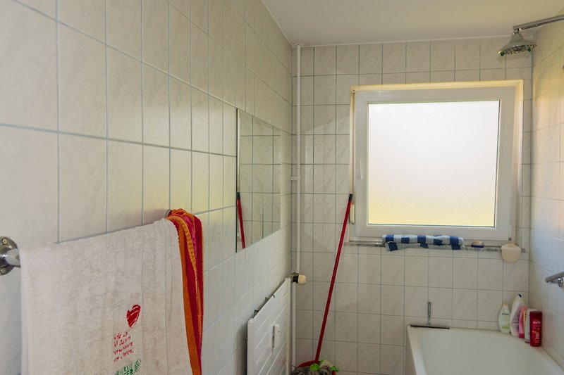 Schönes Badezimmer mit stilvoller Einrichtung und modernen Armaturen mit Termostat. Spiegel gegenüber.