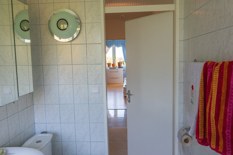 Schönes Badezimmer mit Handtuchhalter. Vom klo kann man durch den Flur in Wohnzimmer schauen zum Fenster raus.
