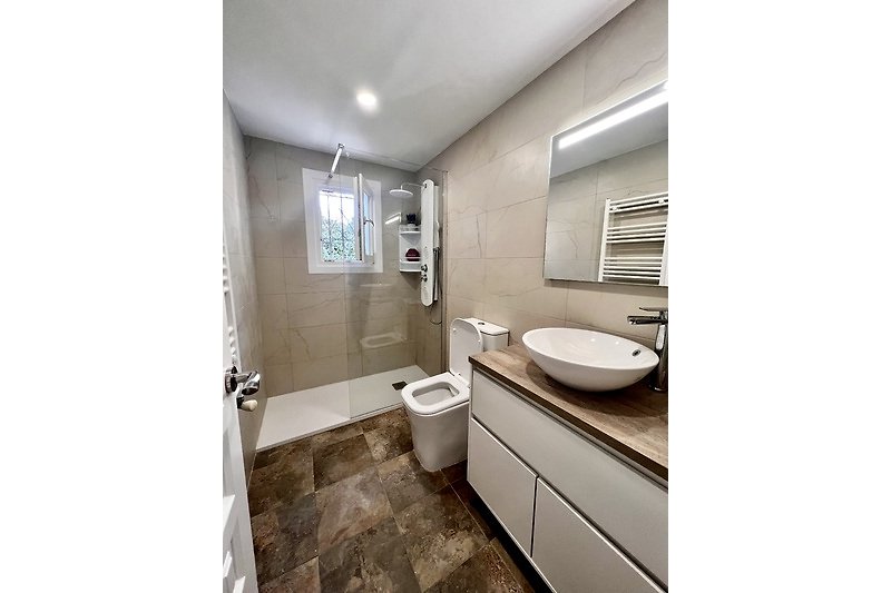 Badezimmer 2 mit elegantem Waschbecken und Spiegel.
