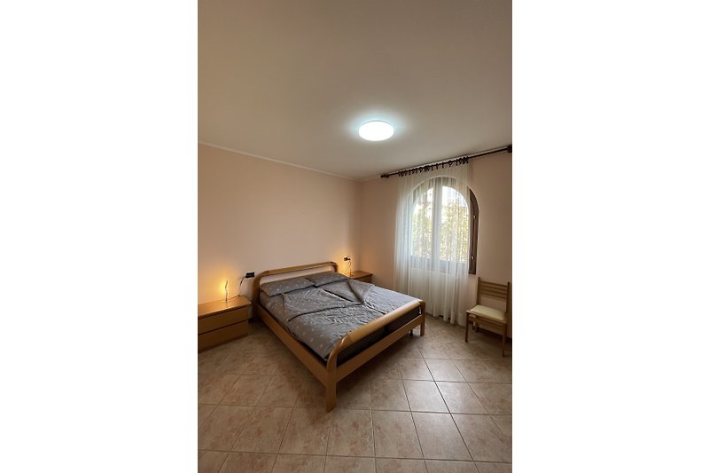 Schlafzimmer mit großem, gemütlichem Bett, stilvolle Beleuchtung