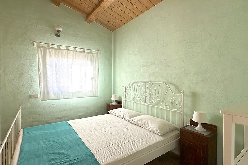 Una camera da letto accogliente con pavimento in legno e arredamento confortevole.