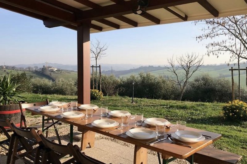 Il porticato con tavolo da pranzo e vista panoramica sulle colline
