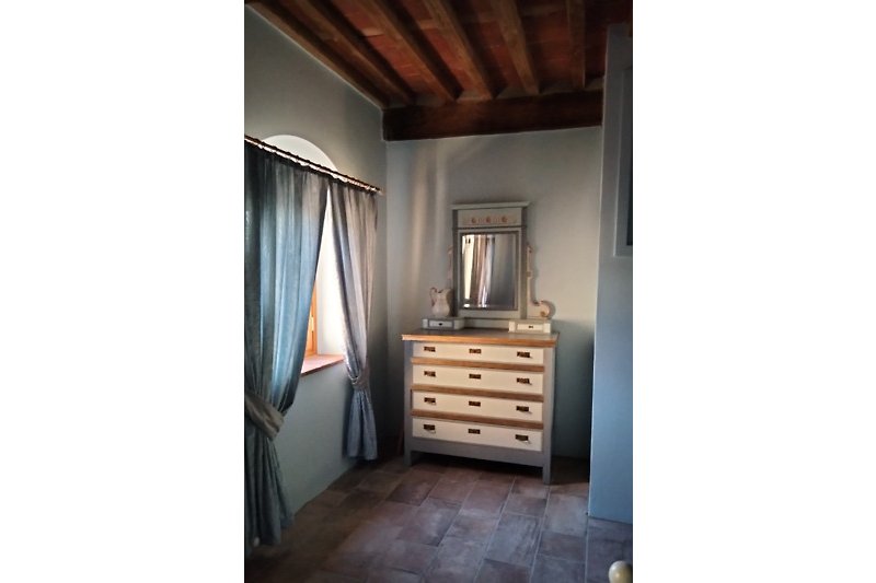 Stilvolles Schlafzimmer mit Holzmöbeln und elegantem Vorhang.