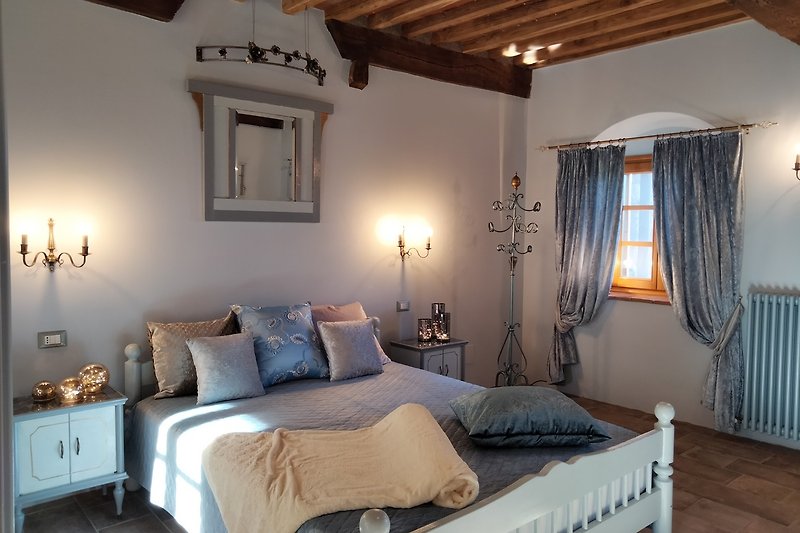 Gemütliches Schlafzimmer mit stilvoller Beleuchtung, bequemem Bett und Blick auf Olivenhaine und den Apennin