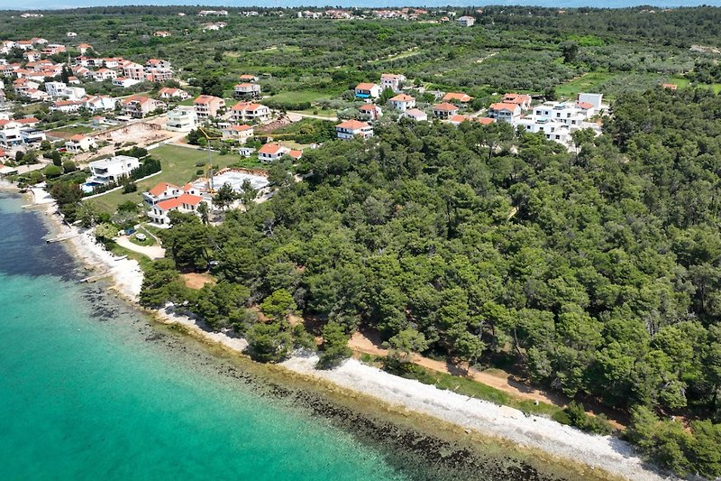 A stunning coastal landscape with a beautiful beach, lush vegetation, and a charming building.
