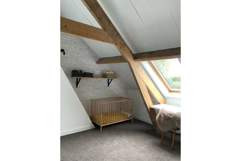 Een comfortabele slaapkamer met houten meubels en een groot raam.