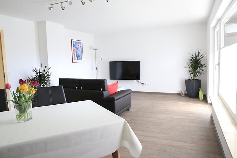 Gemütliches Wohnzimmer mit bequemen Möbeln und großem TV.