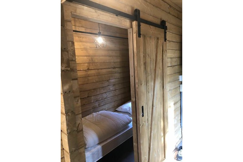 Een comfortabele slaapkamer met loftdeur. Alle bedden worden worden opgemaakt.