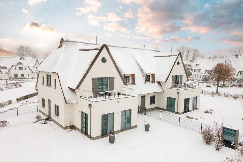 Gemütliches Haus mit Schnee, Holz und einer winterlicher Umgebung.