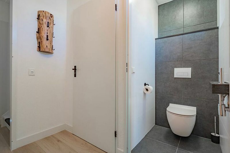 Mooie badkamer met houten vloer, kunst en glazen deur.