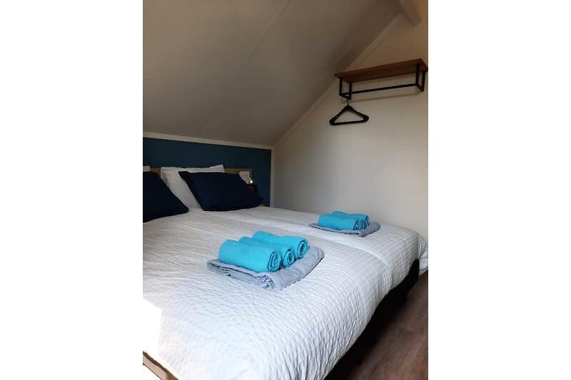 Comfortabele slaapkamer met houten bedframe en zachte beddengoed.