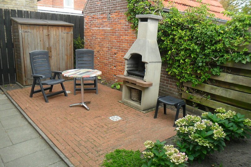 Private Terrasse mit Grill und Gartenschrank.