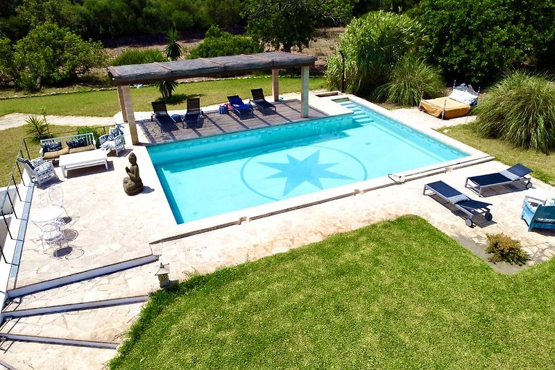 Schwimmbad mit Sonnenliegen und grünem Garten.