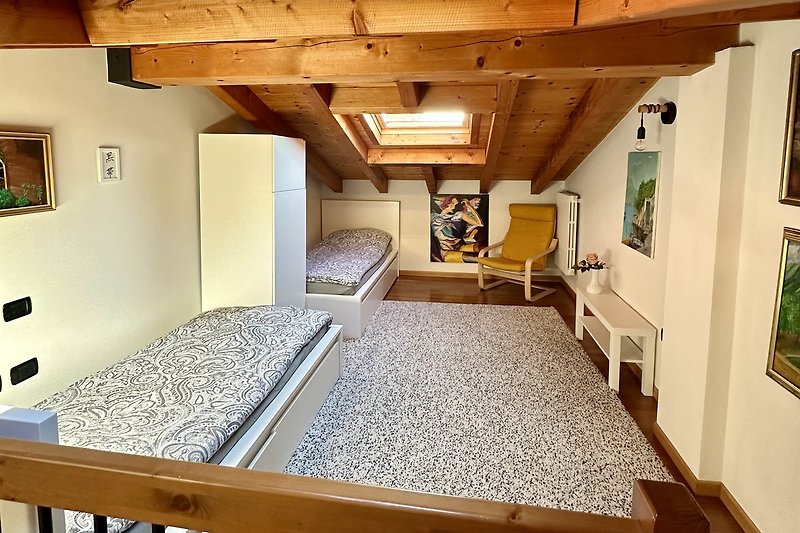 Ein helles Zimmer mit Holzbalken, Pflanzen und Deckenleuchte.