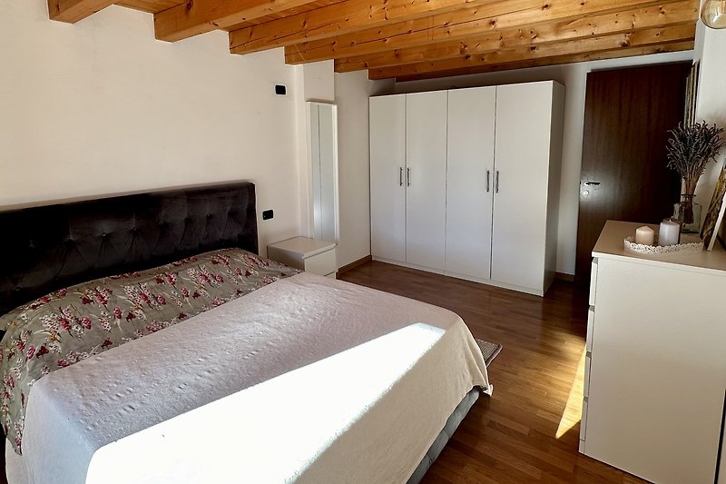 Ein gemütliches Schlafzimmer mit Holzmöbeln, Bett und Pflanze.