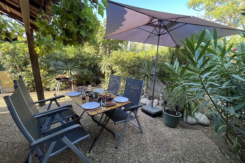 Terrasse mit Tisch, Stühlen, Grill Möglichkeit und Blumen