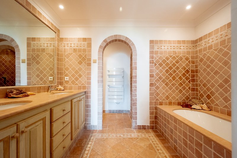 A modern bathroom with stylish cabinetry, a bathtub, and elegant lighting.